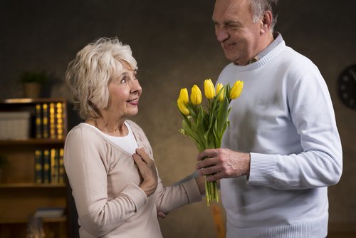 Example of a random act of kindness, an elderly couple where the husband is giving his wife flowers.