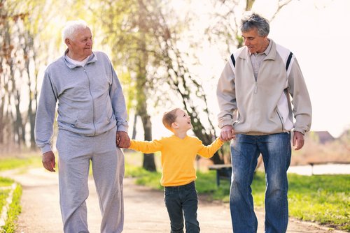 Grandfather, father, and son walking through the park.