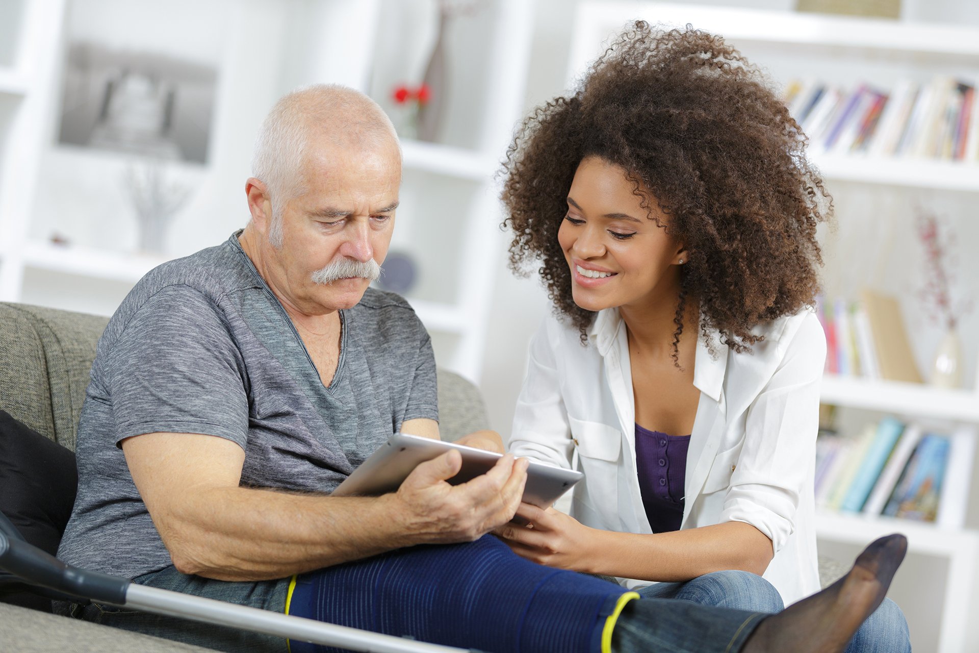 Woman care manager sharing ipad with elderly man